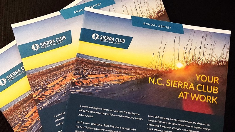 Copies of the 2023 NC Sierra Club annual report are fanned out on a dark background