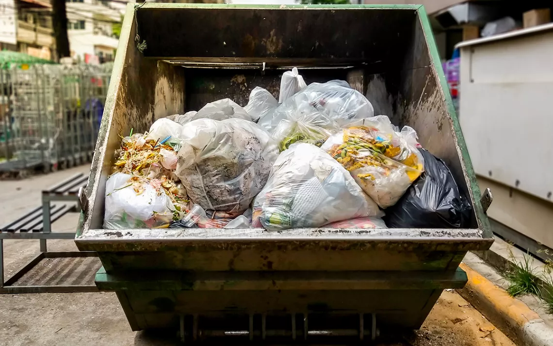 Photo of the back of a dump truck, open to reveal a rainbow-colored heap of produce.