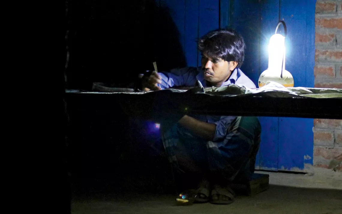 Sufiyan, a 32-year- old embroiderer, regularly stitches until midnight beside a  solar-charged lantern.