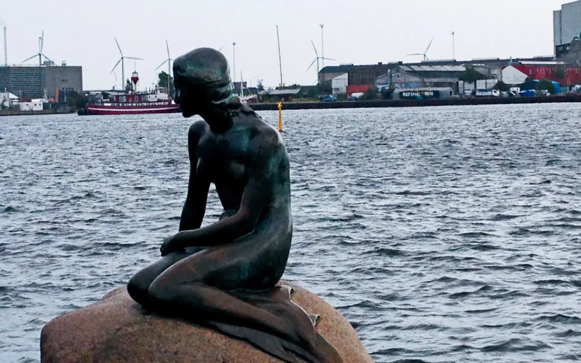 The Little Mermaid in Copenhagen’s harbor is framed by turbines.