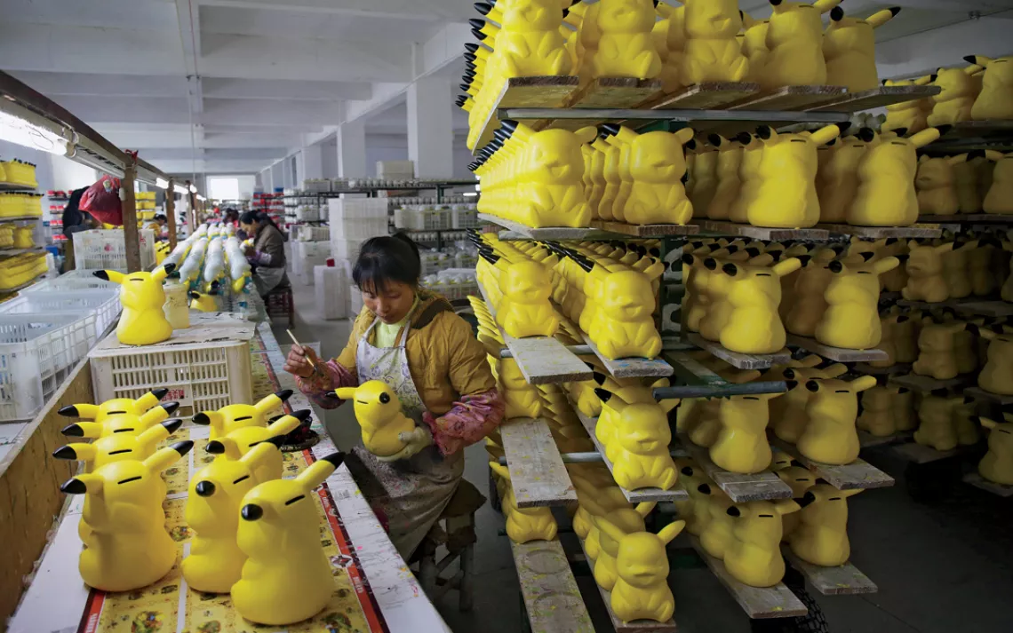 A worker paints money boxes in the shape of cartoon character Pikachu at a pottery factory in Dehua, Fujian province December 7, 2014. Picture taken December 7, 2014