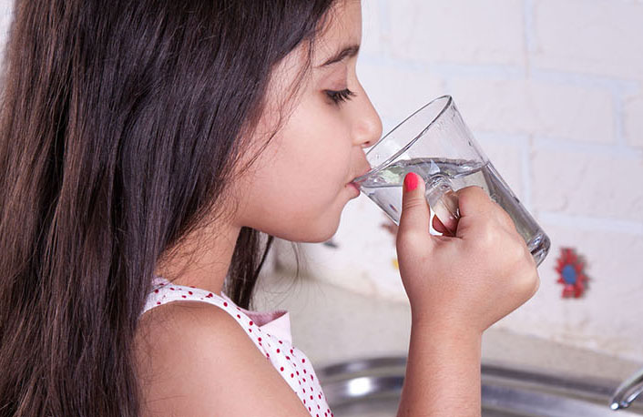 Girl drinking from a water faucet