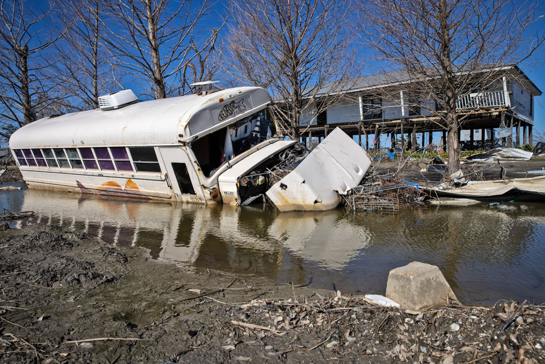 A swamped schoolbus resting in a puddle, bearing a local hotel’s logo.