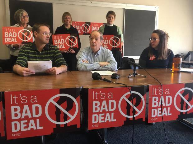 People hold signs that read "It's a bad deal"