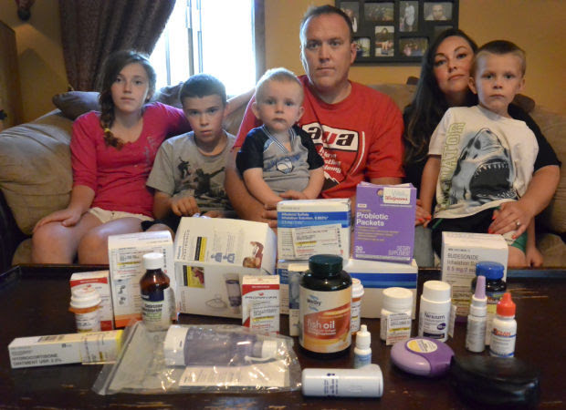 Bill, his wife, and 4 children gathered around a table with all of their medicine they need to take due to the coal