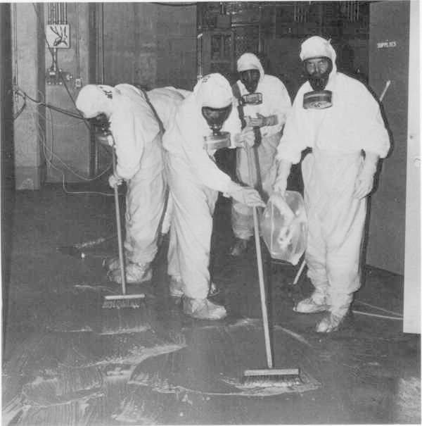 Workers in HAZMAT suits and gas masks clean radioactive waste at Three Mile Island