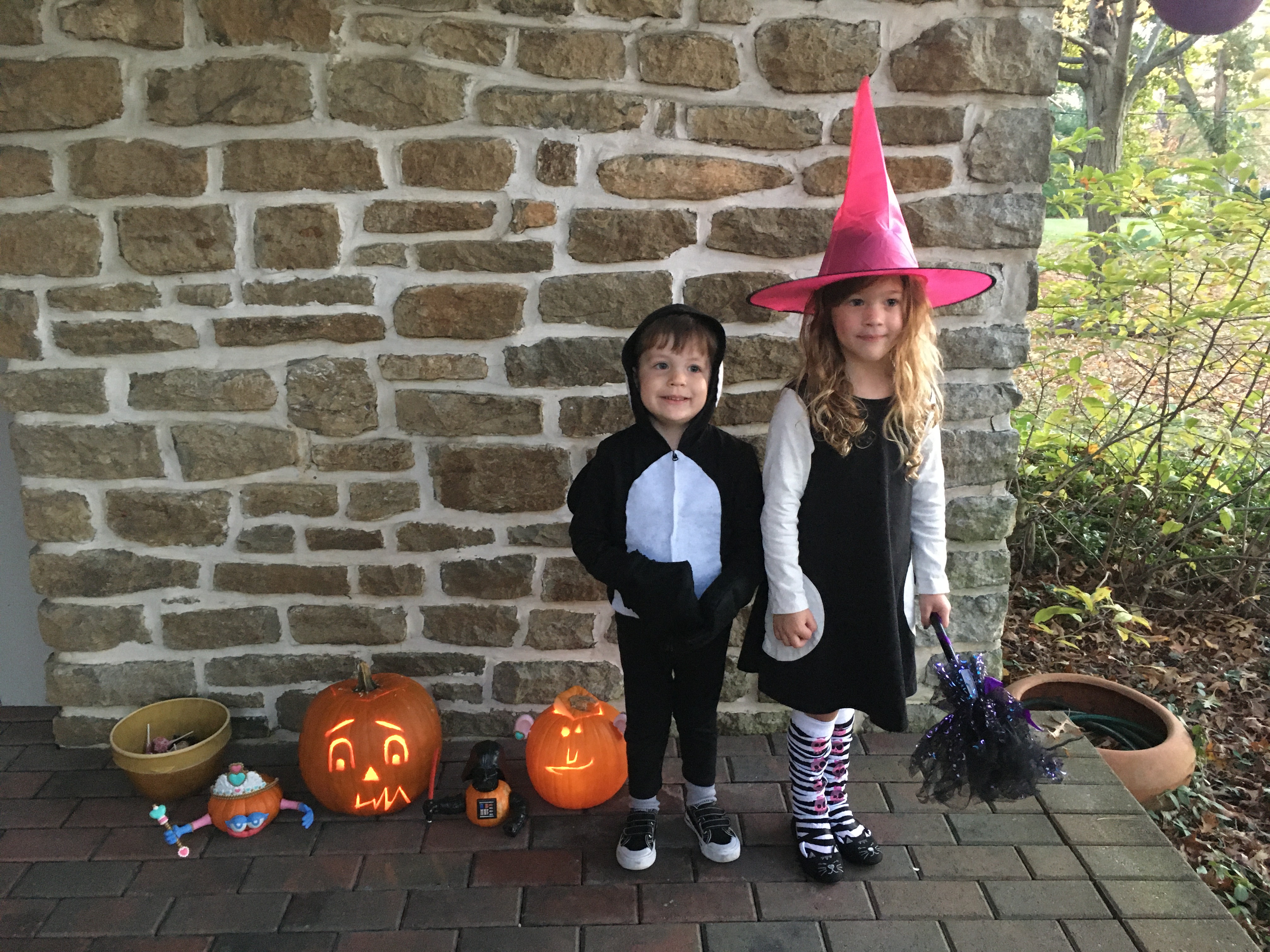 Two children dressed up for Halloween, one dressed as an orca, another dressed as a witch