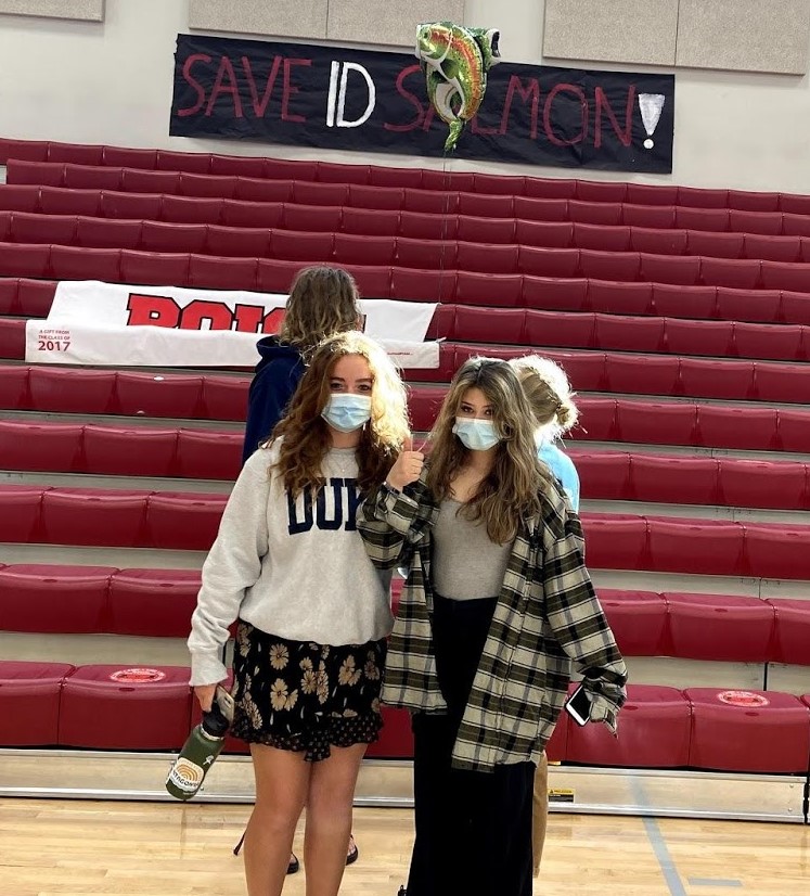 Two high school students standing beneath a hand-painted banner that says "Save ID Salmon"