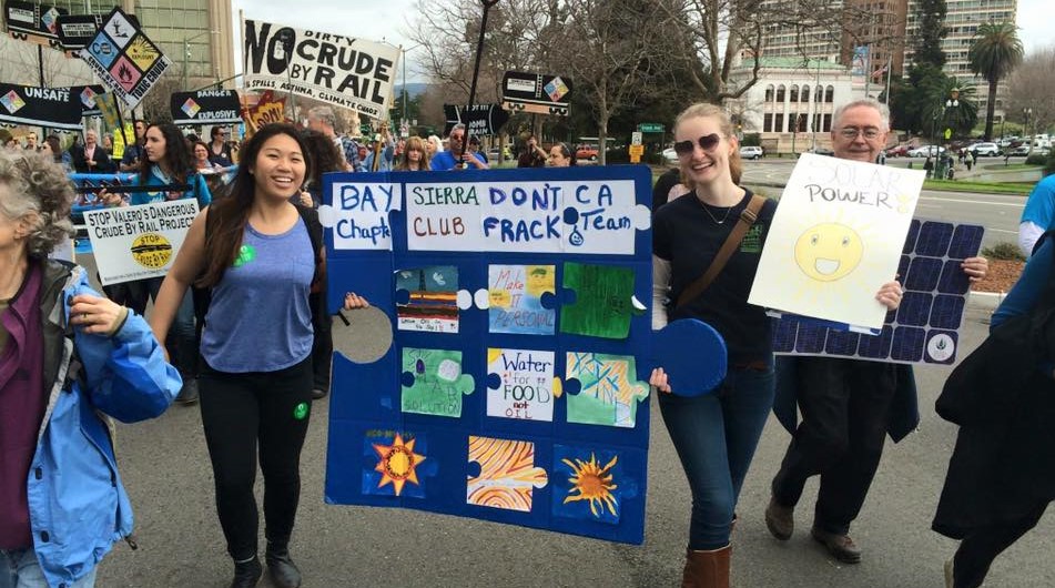 Sierra Club members marching in the streets with signs protesting dirty energy.