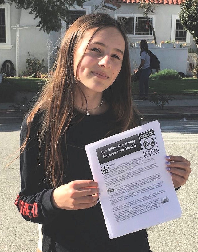 Amelia Blevins holds a flyer entitled "Car Idling Negatively Impacts Kids'Health" 