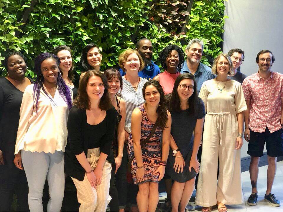 Ready for 100 Organizers and National Staff from across the country smile in front of a luminescent leafy green background