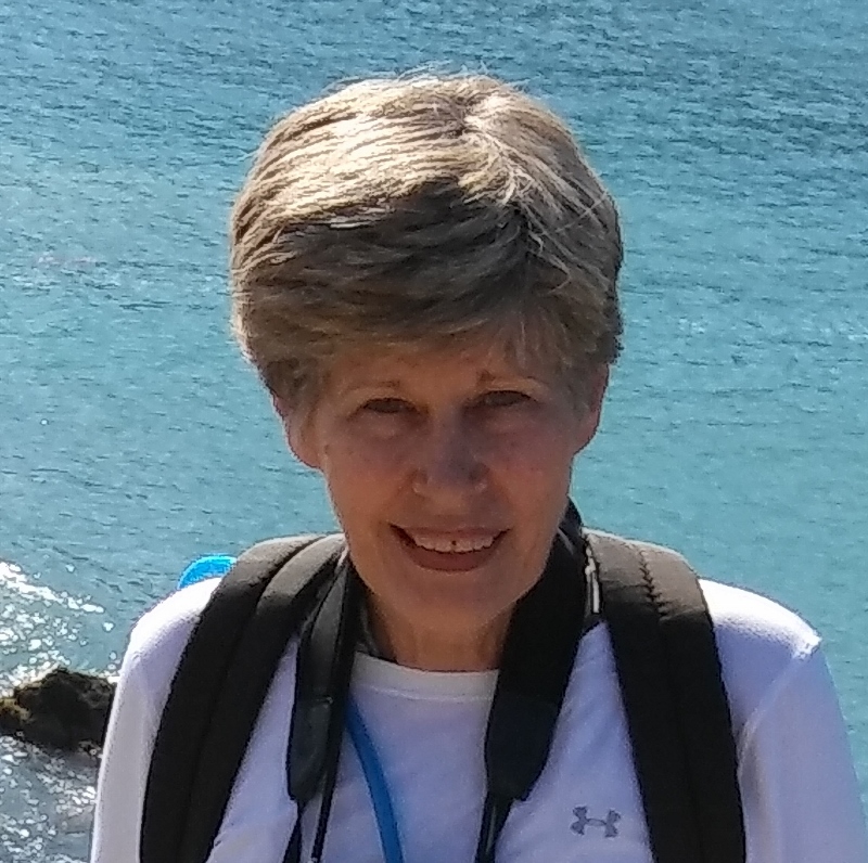 Linda Benson, a woman with short hair smiling, with the sea in the background