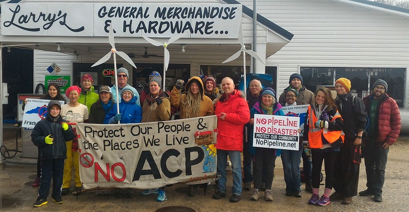 A group of people pose with signs at a country store during a march in opposition to the Atlantic Coast Pipeline