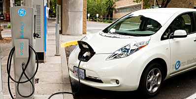 A white electric car is parked and plugged in at a charging station