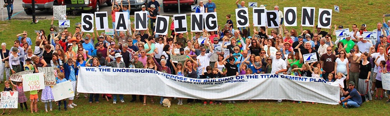Titan protesters hold signs that read "STANDING STRONG" and a large petition