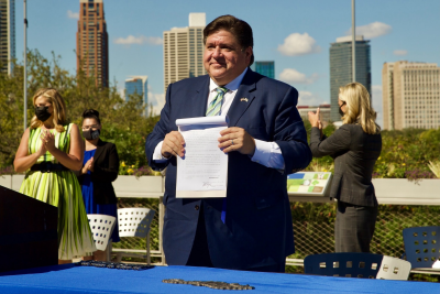Governor JB Pritzker holds the Climate and Equitable Jobs Act after signing it into law at the Shedd Aquarium in Chicago. 
