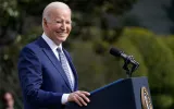 President Joe Biden smiles at a podium 