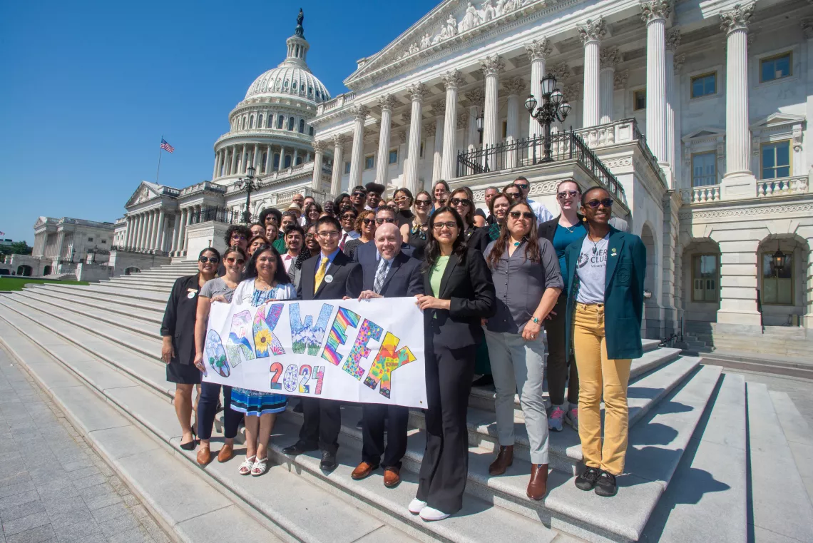 A group pose in front of Capitol Hill holding a banner that says "OAK Week 2024"