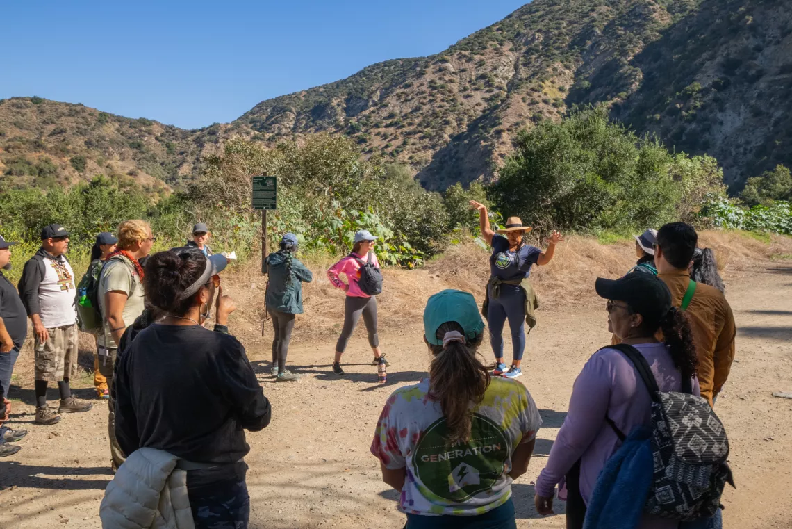 People stand in a circle around someone talking at the base of the San Gabriel Mountains