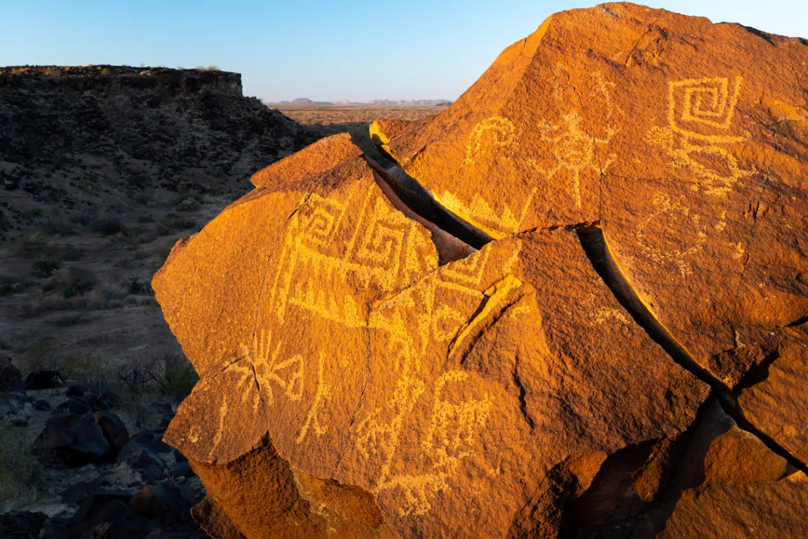 Prehistoric petroglyphs on rocks warmly lit by a sunset