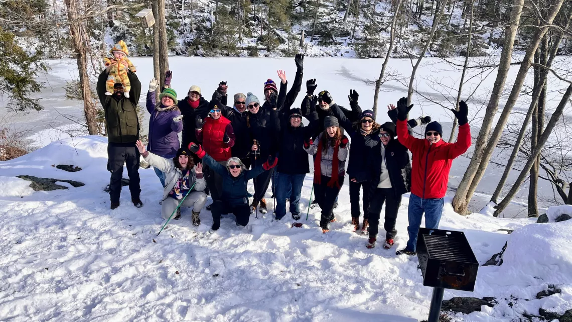 A group of people posing in the snow with their arms up