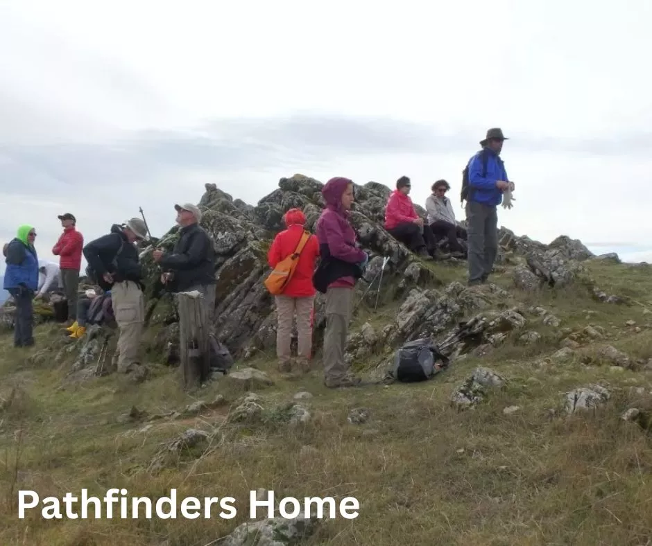 Pathfinders Home -- Hikers at the top of a peak under a grey sky