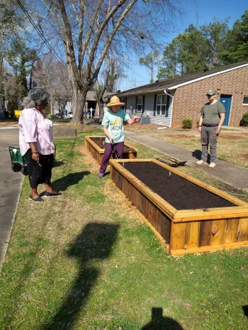 3 people standing near raised beds