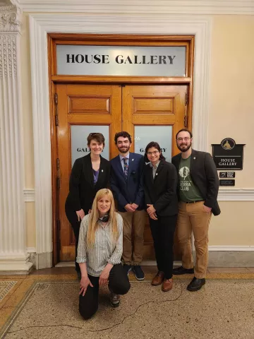 Chapter staff and volunteers standing and smiling in front of a room labeled "House Gallery"