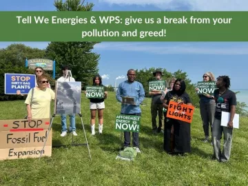 A group of people standing on the shore of Lake Michigan holding signs opposing the We Energies gas expansion and rate hikes.