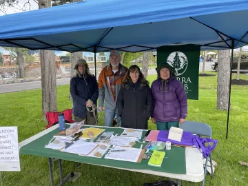 Sierra Club members under a tent canopy, behind a table