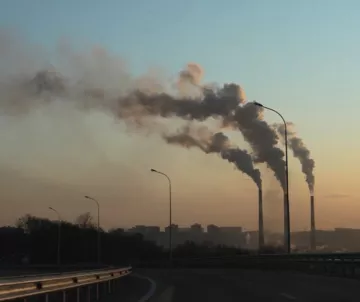 climate action: three smokestacks against smoggy sky