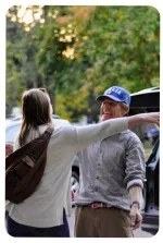 two adults smiling at each other and holding out arms for hug