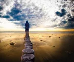 Person on a beach looking toward blue sky with clouds