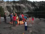 Group of adults and kids around a campfire