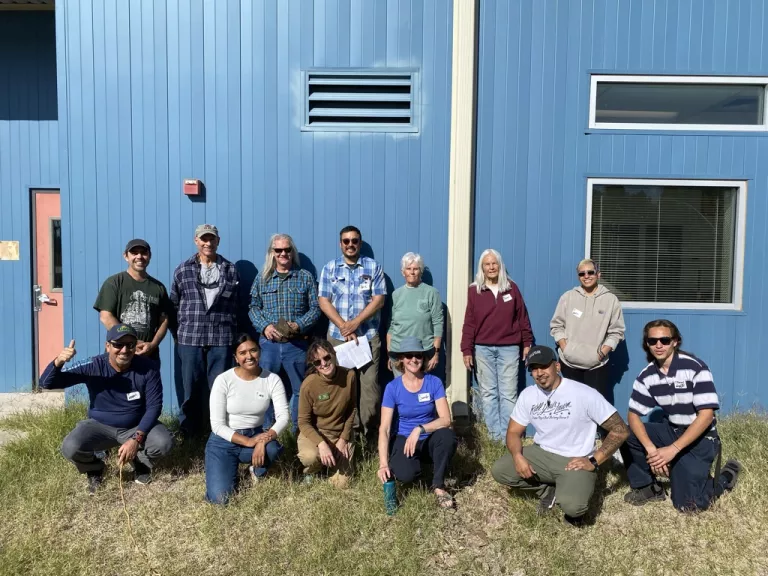 Photo of a group of people smiling in front of a building