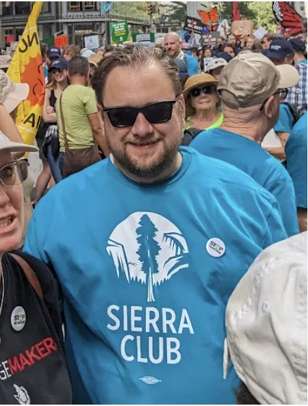Christopher Shepherd in a blue Sierra Club logo tee, in a group outdoors.