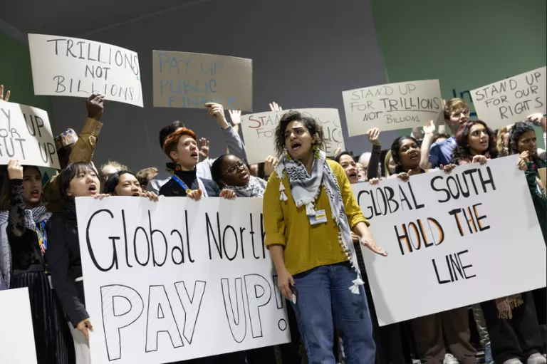 Protesters assembled at COP-29 demanding climate justice with signs