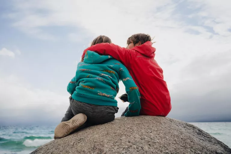 kids sitting on the rock at the beach