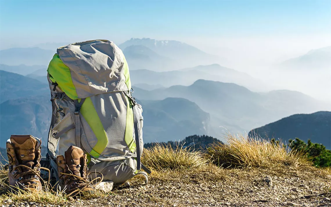 Hiking equipment. Backpack and boots on top of the mountain. | Photo by Drepicter/iStock