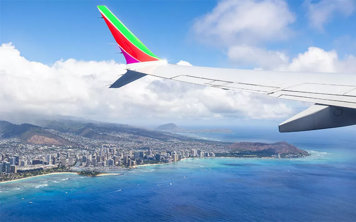 A plane flying over blue waters off the coast of Hawaii