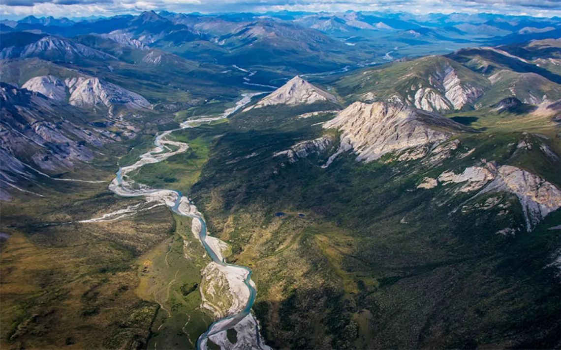 An aerial view of the Brooks Range, with a stream flowing through a valley