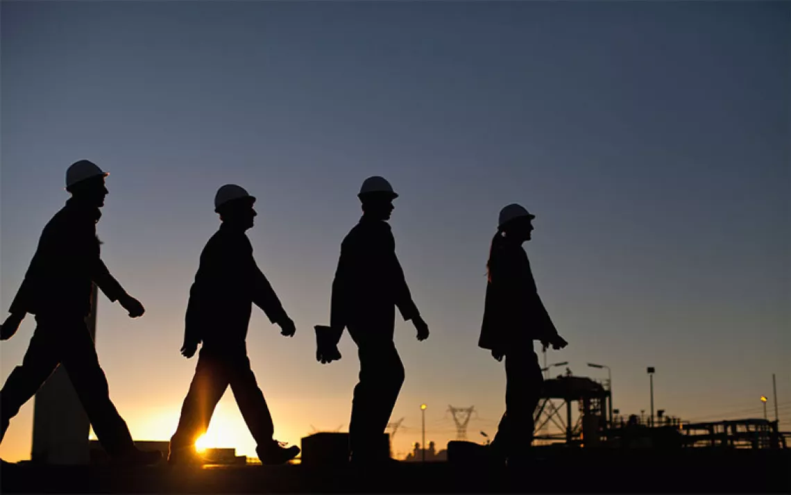 Silhouette of workers at oil refinery