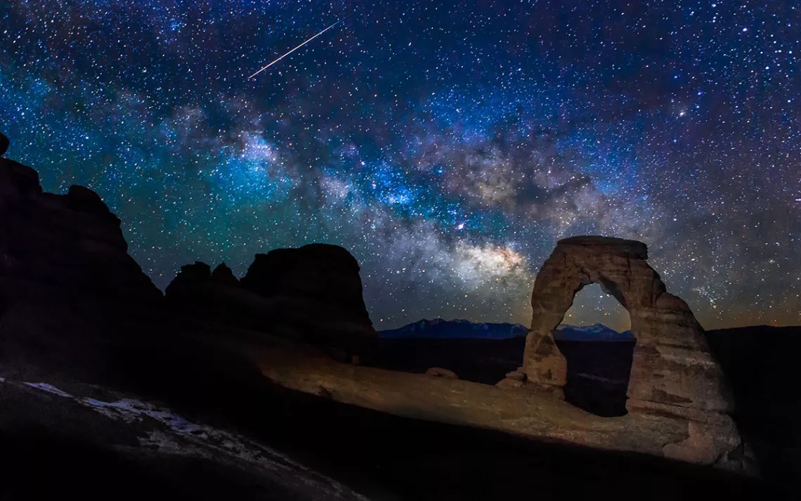 The Milky Way over a red rock arch. 