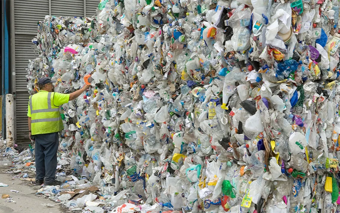 Man examines bales of plastic waste bottles