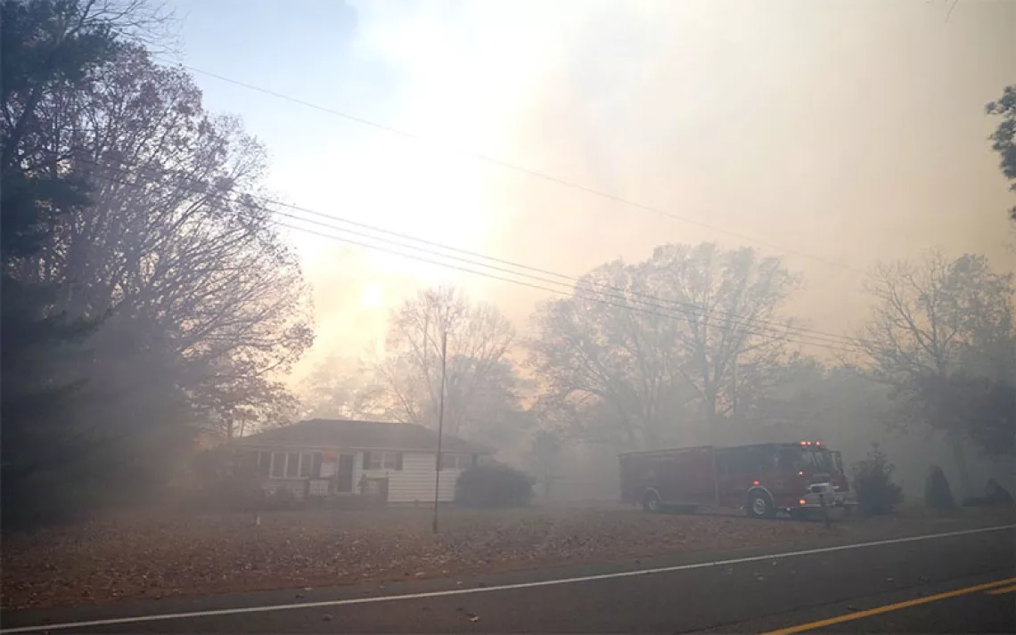 Smoke fills the air around a suburban ranch-style house with a firetruck parked out front