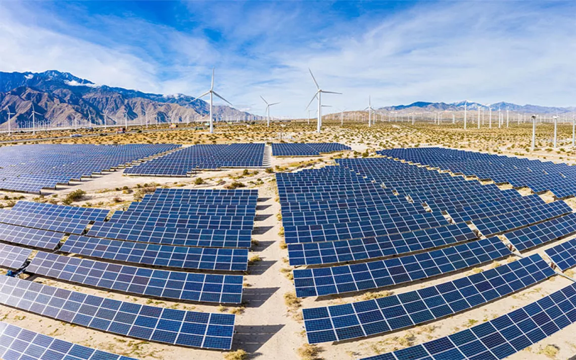 A field of solar panels and windmills in the desert. | Photo by adamkaz/Getty Images