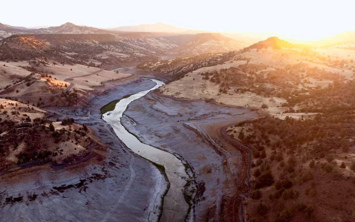 Aerial photo of Klamath River flowing and the footprint of the former reservoir water line still visible.