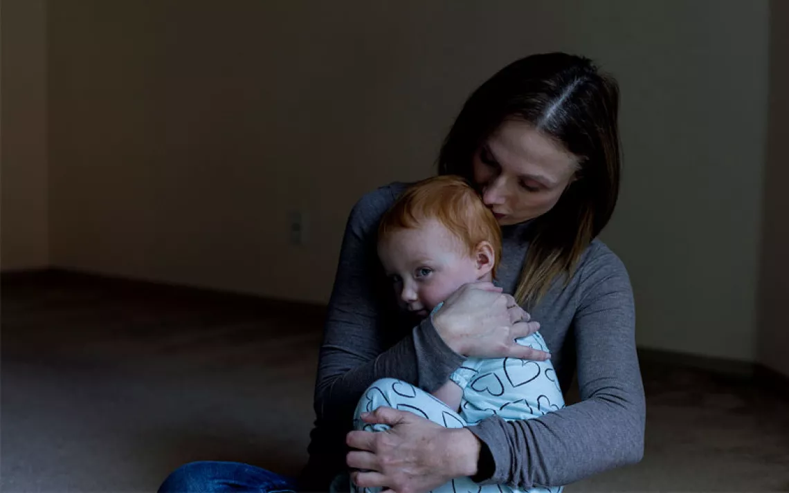 Amy Dishion hugs her toddler, who is looking over her shoulder at the camera