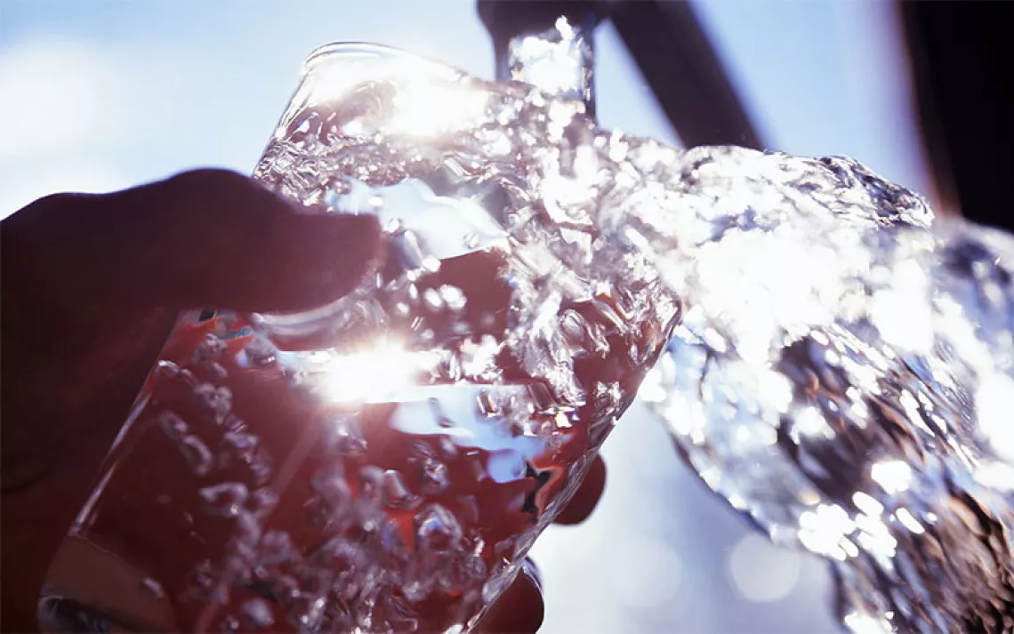 Someone fills their glass full of water from the tap.