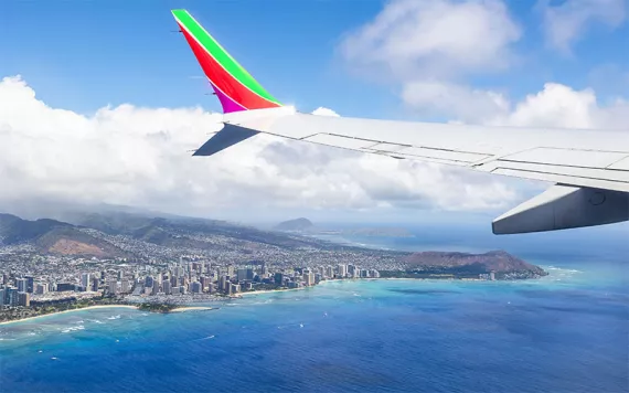 A plane flying over blue waters off the coast of Hawaii